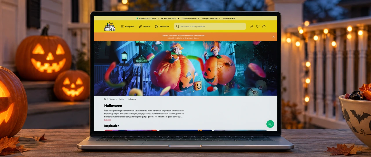 Partykungen's Halloween page open on a laptop on a weathered wooden table on a porch at dusk, between glowing carved pumpkins, a bowl of sweets and a string of warm lights along the railing.
