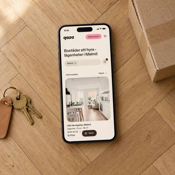 Qasa's page of apartments to rent in Malmö on a phone lying on a herringbone oak floor next to a set of keys.
