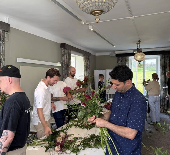 Colleagues binding flower bouquets at a workshop table during the 2025 kickoff
