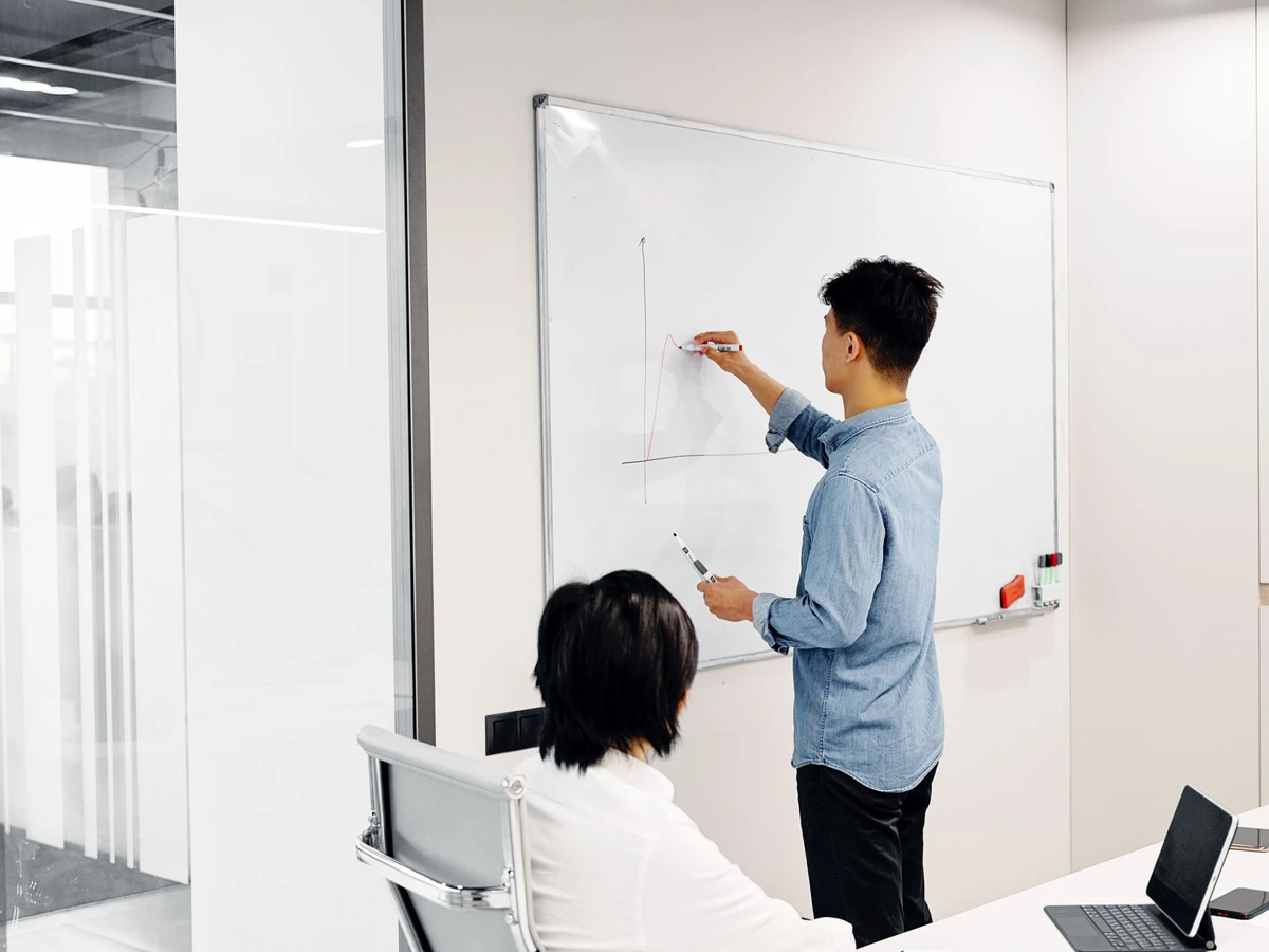 Two people planning at a whiteboard covered in notes