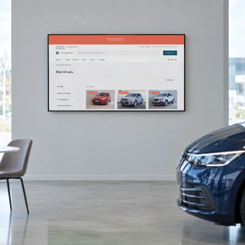 Holmgrens Bil's page Bilar till salu, cars for sale with filters and the first three cars, on a large screen on the wall of a car showroom, with the front of a dark blue car in the corner