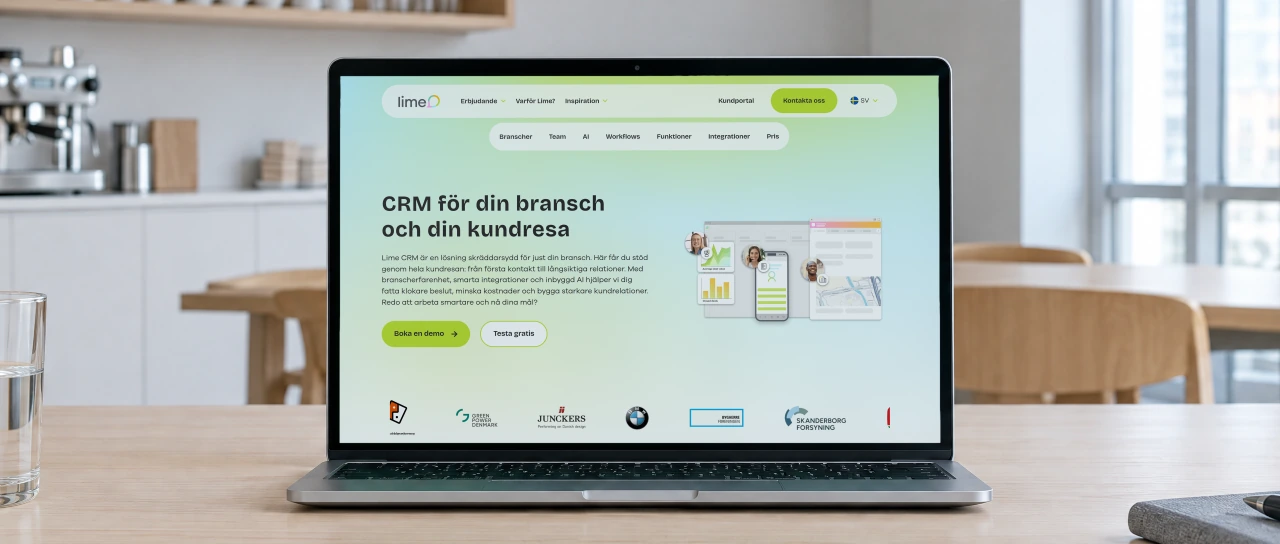 Lime Technologies' page for Lime CRM, “CRM för din bransch och din kundresa”, open on a laptop on an ash table in a bright office kitchen with an espresso machine and white pendant lamps behind.